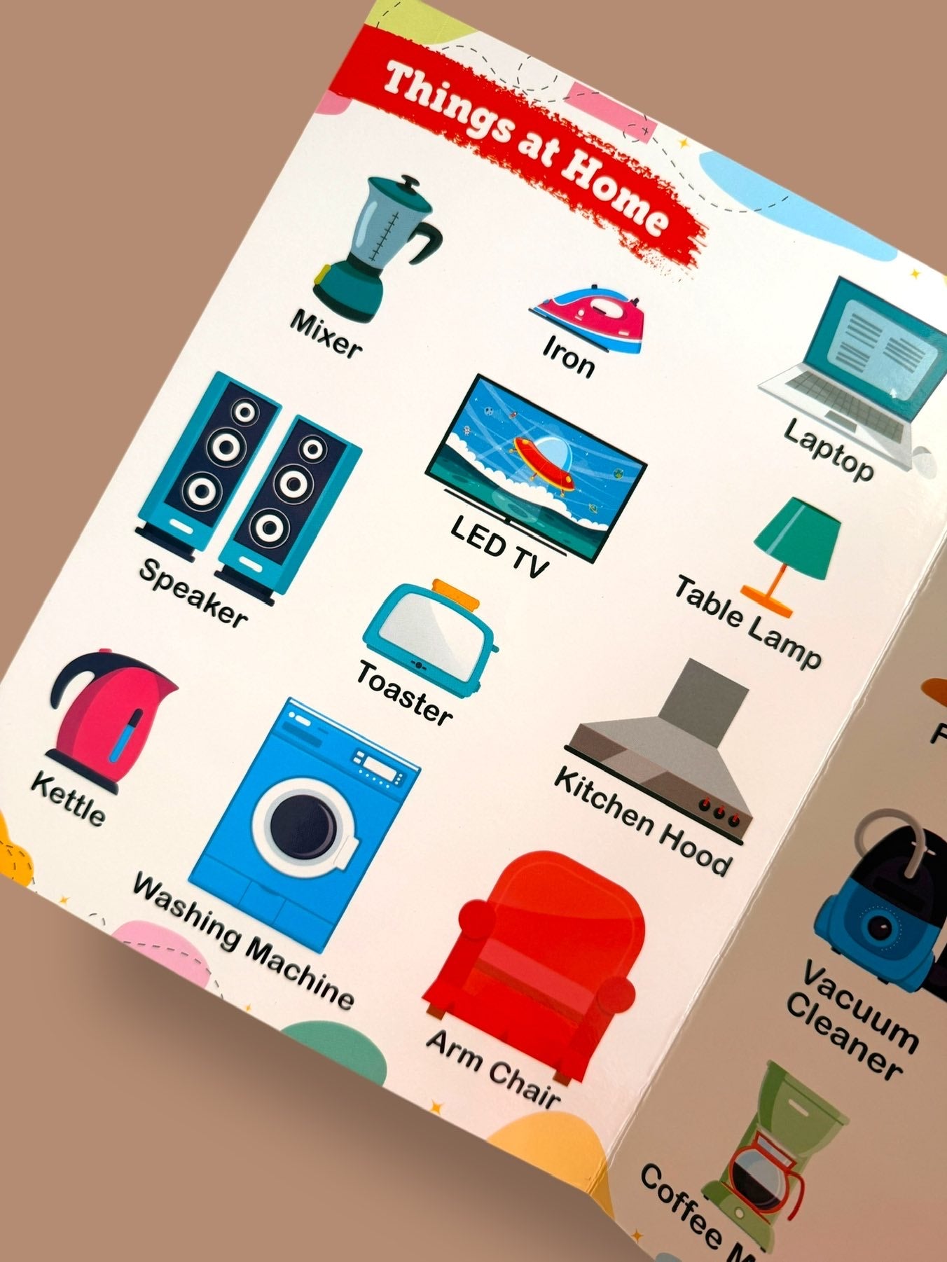 My First Words board book page featuring household objects including mixer, iron, laptop, LED TV, washing machine, toaster, kettle, speaker, table lamp, and armchair
